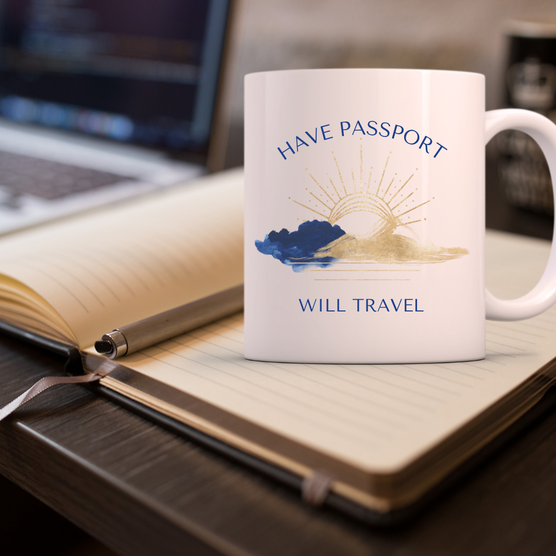 White mug with 'Have Passport, Will Travel' design on a desk with an open notebook and pen.