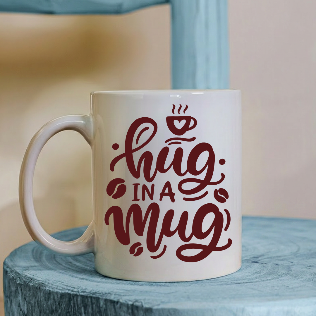 White mug with red text 'Hug in a Mug' on a blue surface
