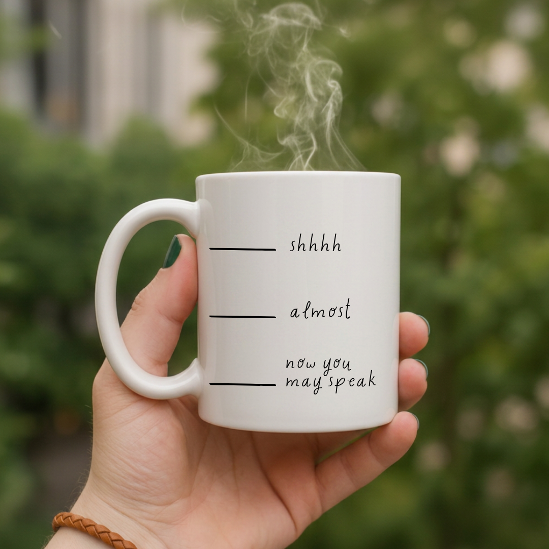 White mug with text held by a hand against a blurred green background