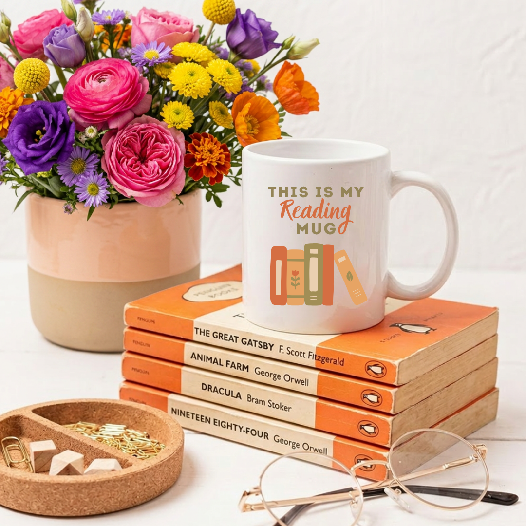 Mug with 'This is my reading mug' text on books with flowers and glasses in the background